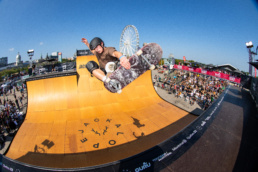 Professional skateboarder doing a trick on a large ramp surrounded by a crowd